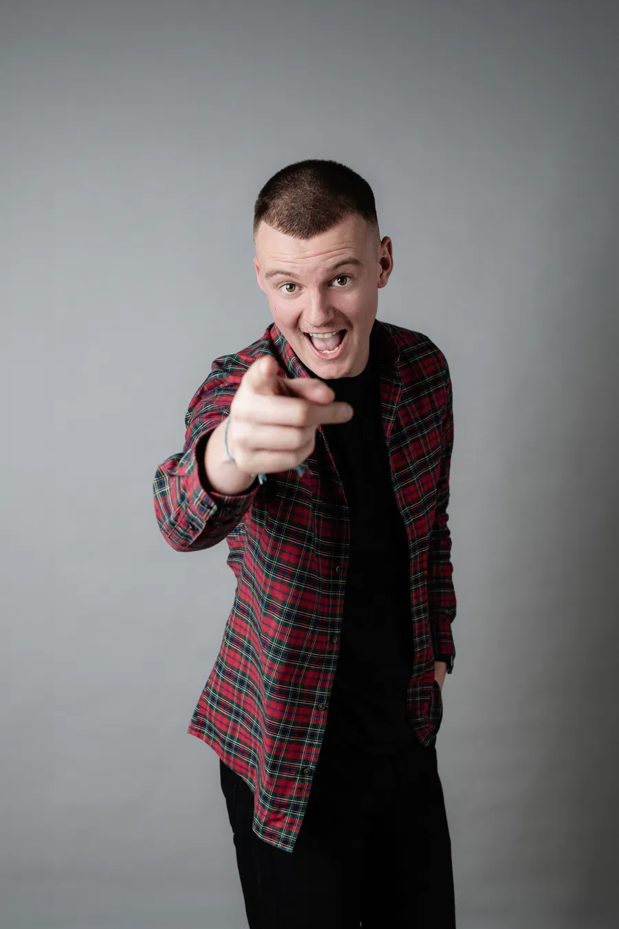 Alex Mitchell, wedding videographer, pointing at the camera and smiling